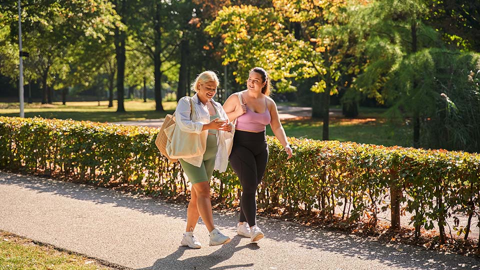 Two women take a walk outdoors on a summer day